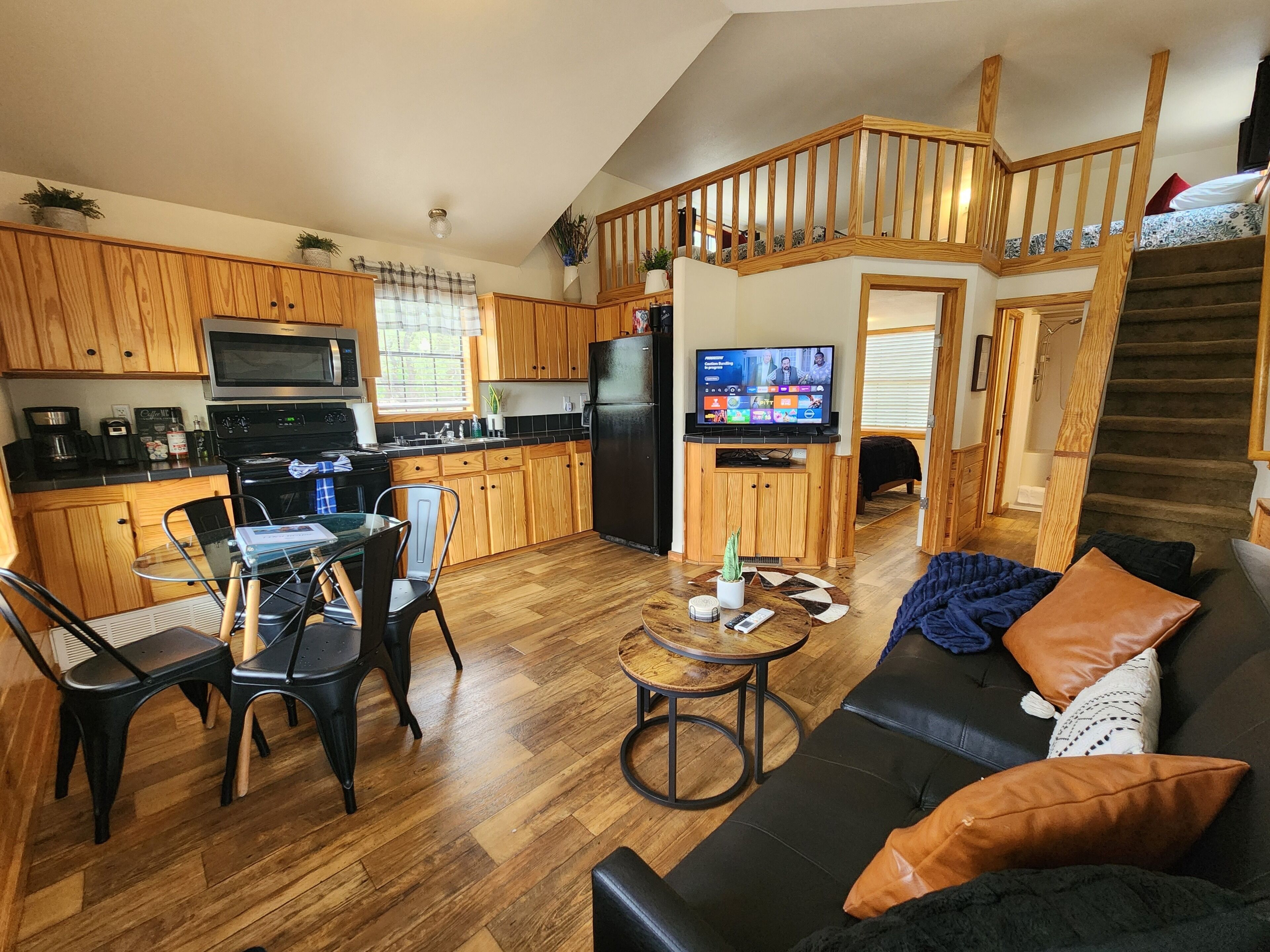 A compact living space with a kitchen, dining area, and a staircase leading to a loft bedroom.