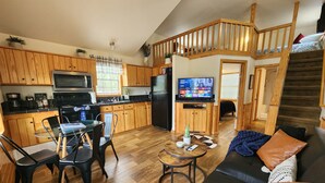 A compact living space with a kitchen, dining area, and a staircase leading to a loft bedroom. - Cozy Canyon Lake Tiny House – Stunning Views & Great Location (Canyon Lake)