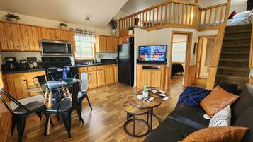 A compact living space with a kitchen, dining area, and a staircase leading to a loft bedroom.