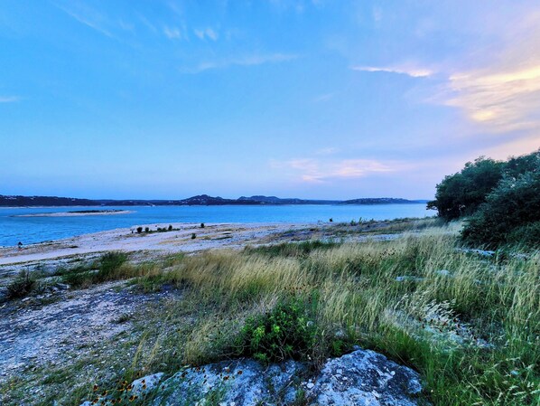 A coastal landscape with a beach, grassy areas, and distant hills. - Cozy Canyon Lake Tiny House – Stunning Views & Great Location (Canyon Lake)