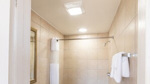A bathroom with a toilet, sink, and shower area. - American Inn (Baton Rouge)