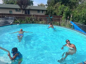 Une piscine à l’eau d’un bleu limpide, entourée d’une clôture en bois et d’arbres.