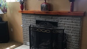 A living room with a fireplace, a decorative wall piece, and a potted plant.