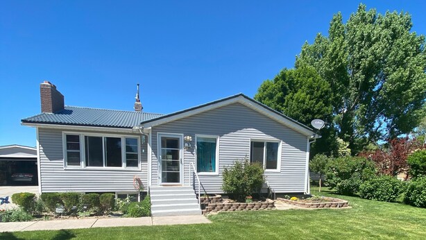 A single-story house with a front porch, a chimney, and a well-maintained lawn.