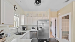 A modern kitchen with white cabinets, stainless steel appliances, and a countertop with a black induction cooktop.