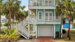 A two-story building with a white balcony, a garage, and a staircase leading to the entrance.