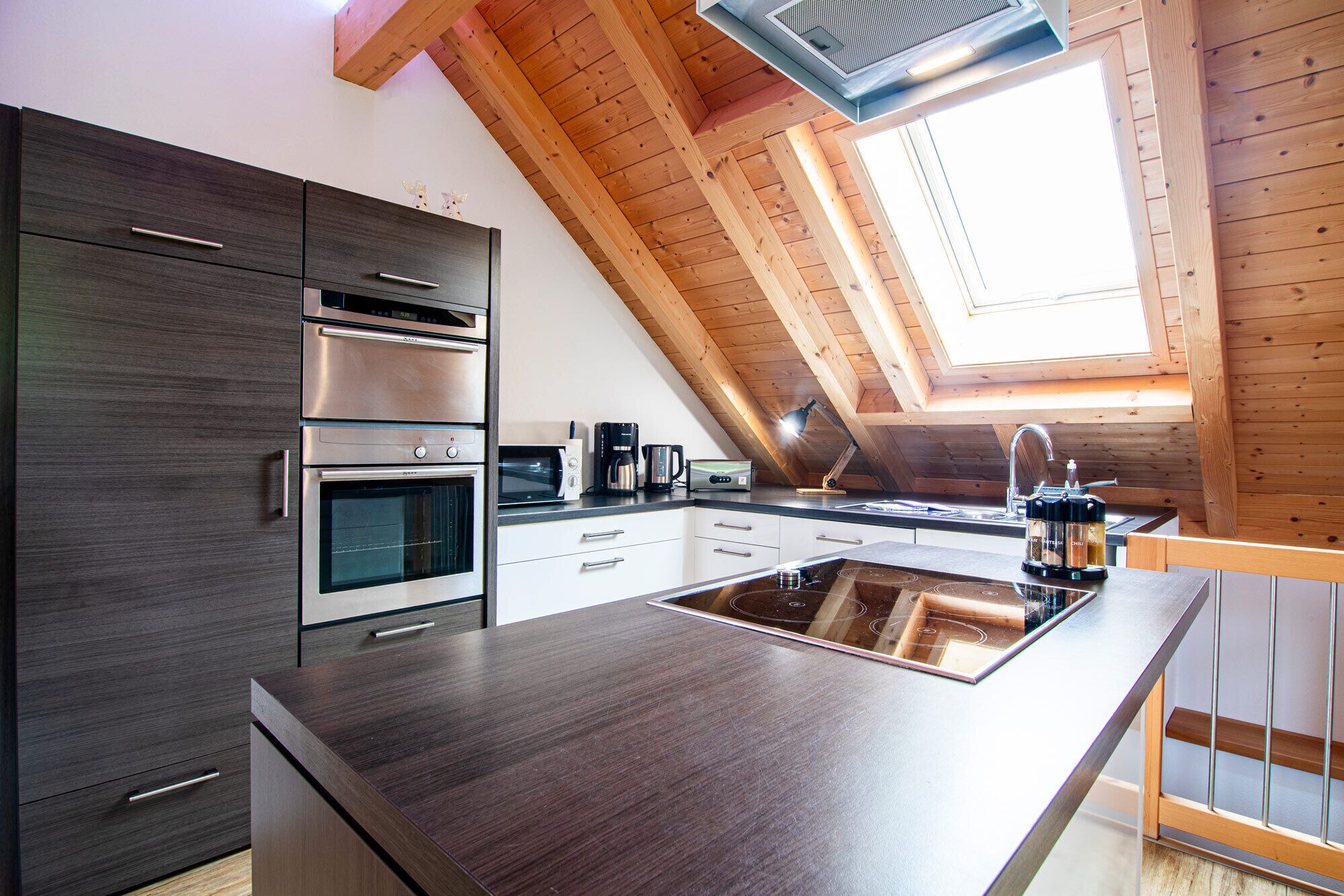 Une cuisine moderne dotée d’appareils électroménagers intégrés, d’un grand îlot central et d’une lucarne.