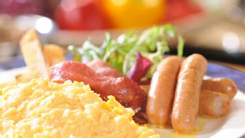 A plate with scrambled eggs, sausages, and bacon.