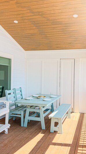 A covered patio with a wooden ceiling, white walls, and a table set for dining. - OCEAN VIEW, across from beach access, BEAUTIFULLY updated 4 bed,4 bath,sleeps 14 (Emerald Isle)