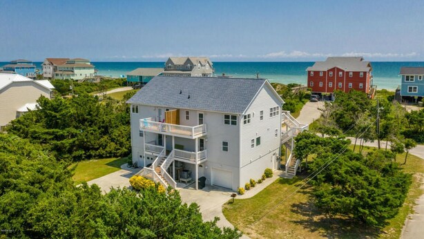 Een tweelaags huis met een balkon, een garage en uitzicht op de oceaan.