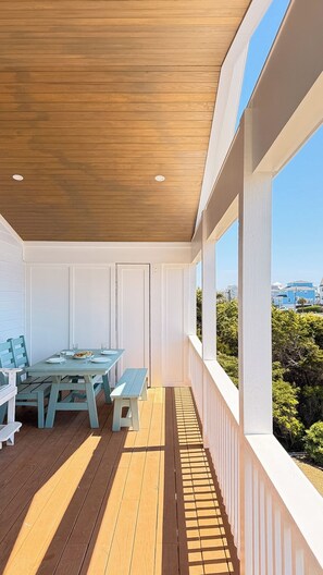 A covered outdoor area with a wooden ceiling, white walls, and a view of the cityscape.