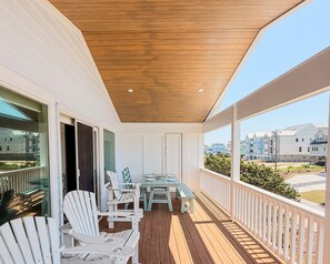 A covered outdoor area with a wooden ceiling, white railings, and a view of buildings in the background.