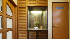Une porte en bois avec une petite fenêtre, un meuble en bois orné d’une plante en pot et un certificat encadré placé sur le meuble.