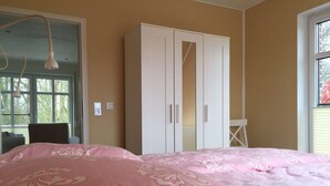 A bedroom with a bed, a wardrobe, a desk, and a chair. - Huus Windroos (Jemgum)