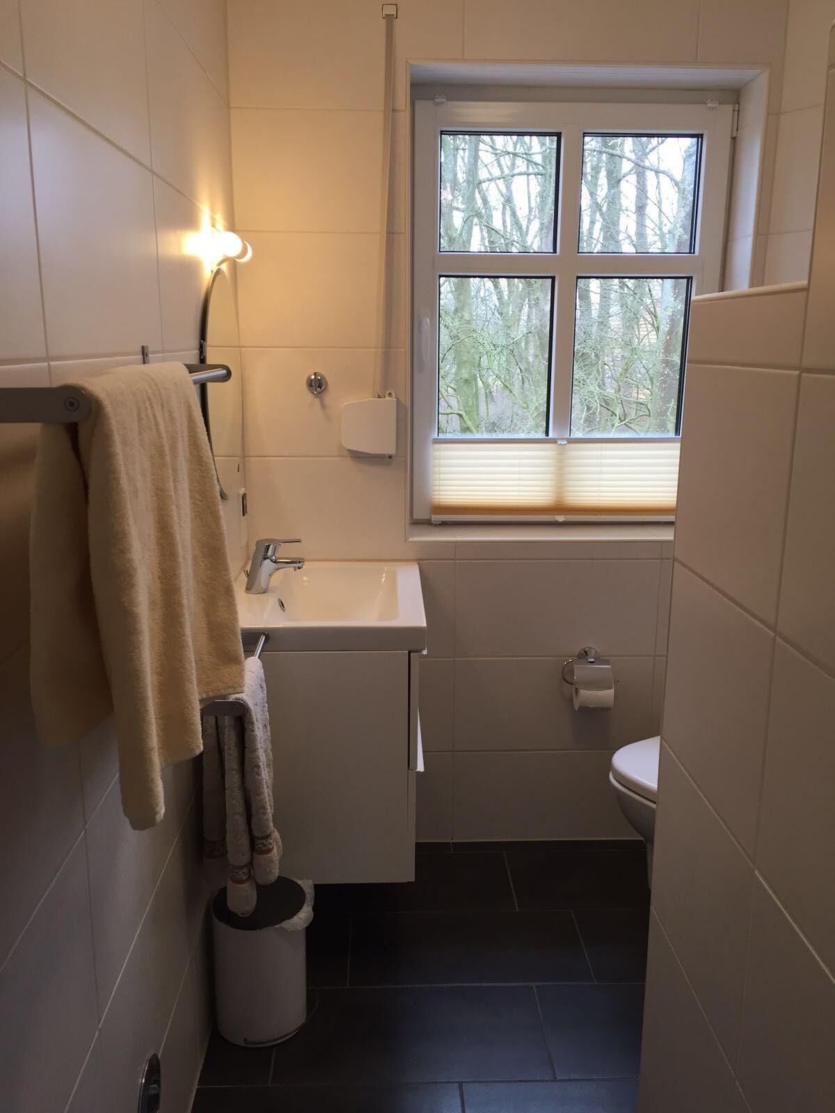 Un baño pequeño con lavamanos, inodoro y ventana.