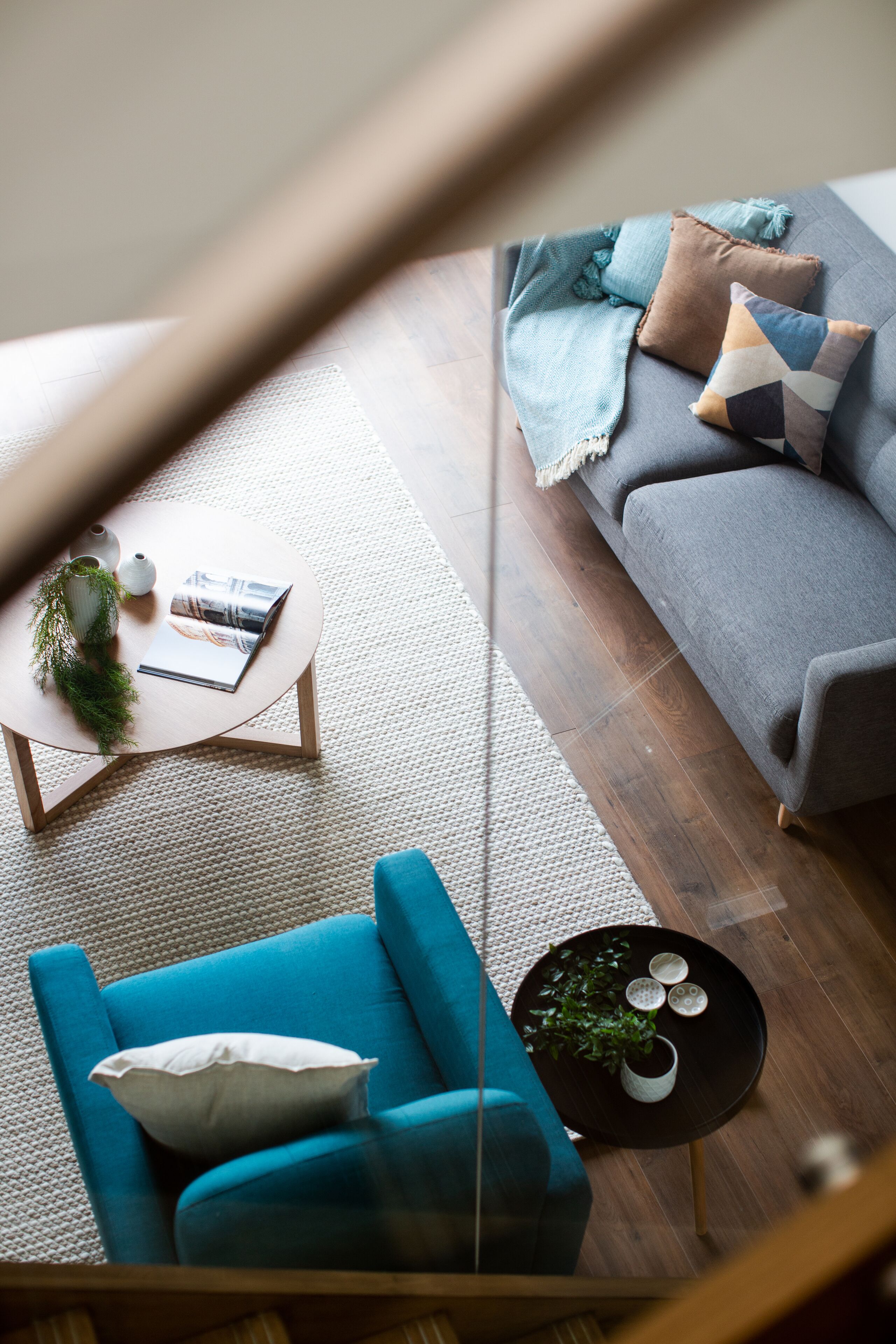 Una sala de estar moderna con un sofá azul, un sofá gris, una mesa de centro redonda y una mesita auxiliar con una planta.