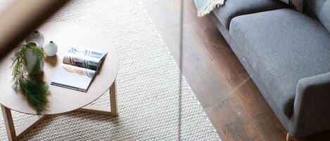 Una sala de estar moderna con un sofá azul, un sofá gris, una mesa de centro redonda y una mesita auxiliar con una planta.