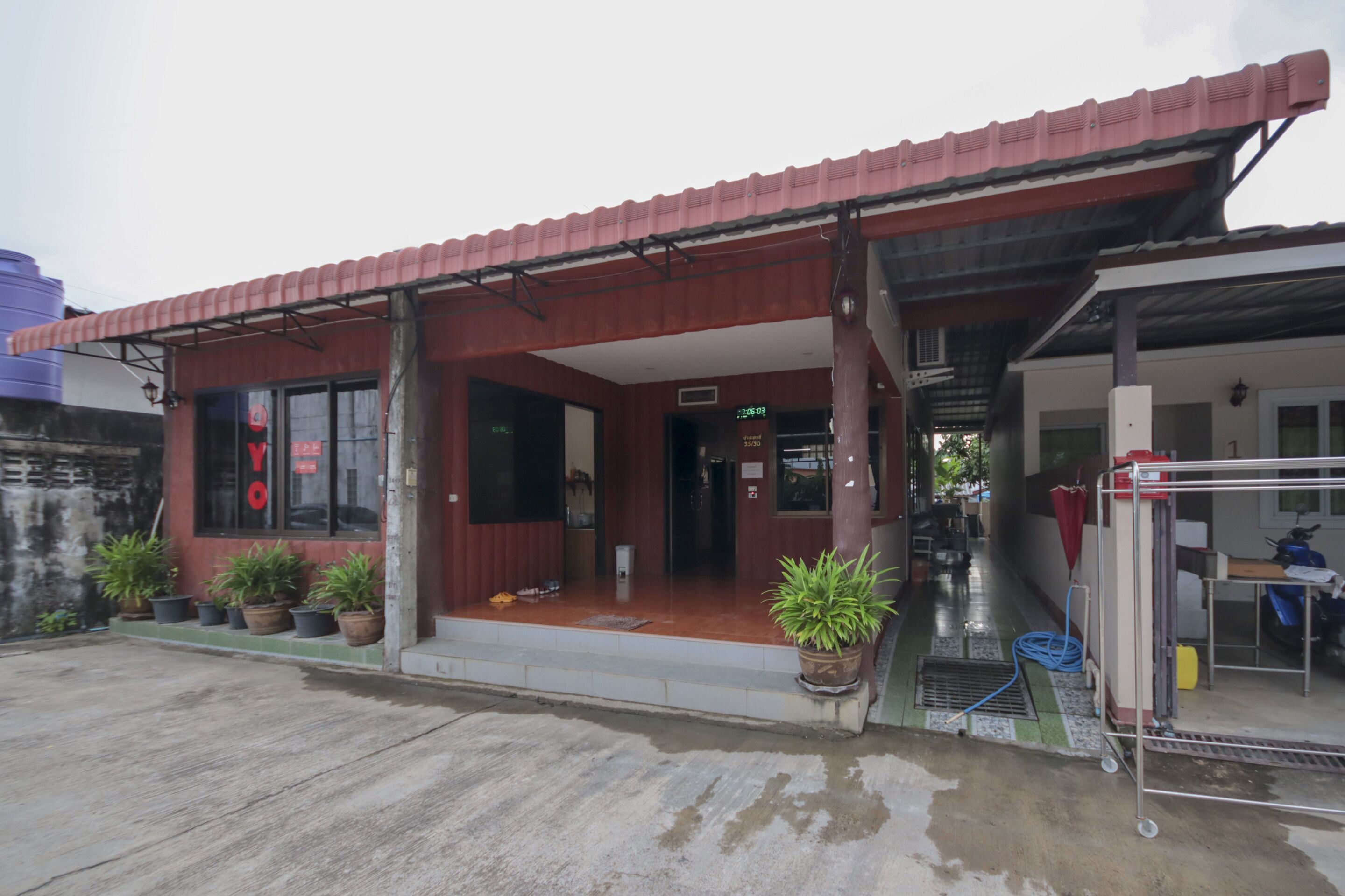 A small building with a red roof, a front entrance, and potted plants outside.