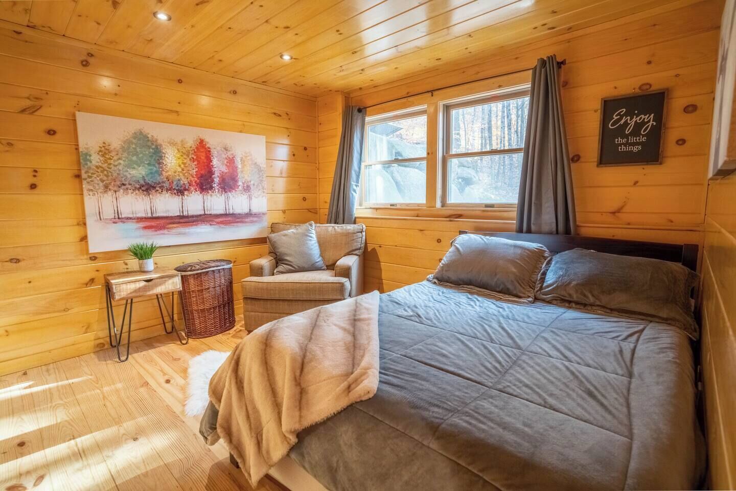 Une pièce dans un chalet en bois, comprenant un lit, une chaise, un tableau et une fenêtre.