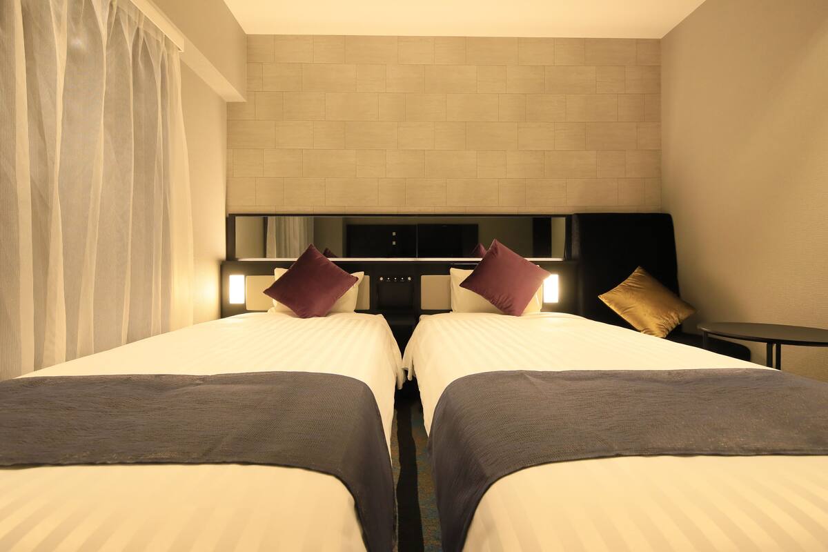A hotel room with two beds, a TV, and a small table.