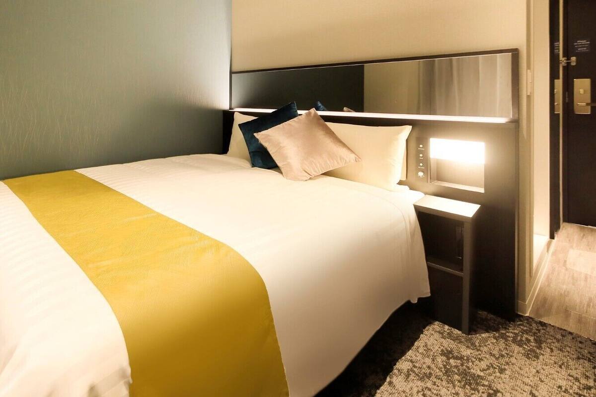 A hotel room with a bed, bedside table, and a nightstand.