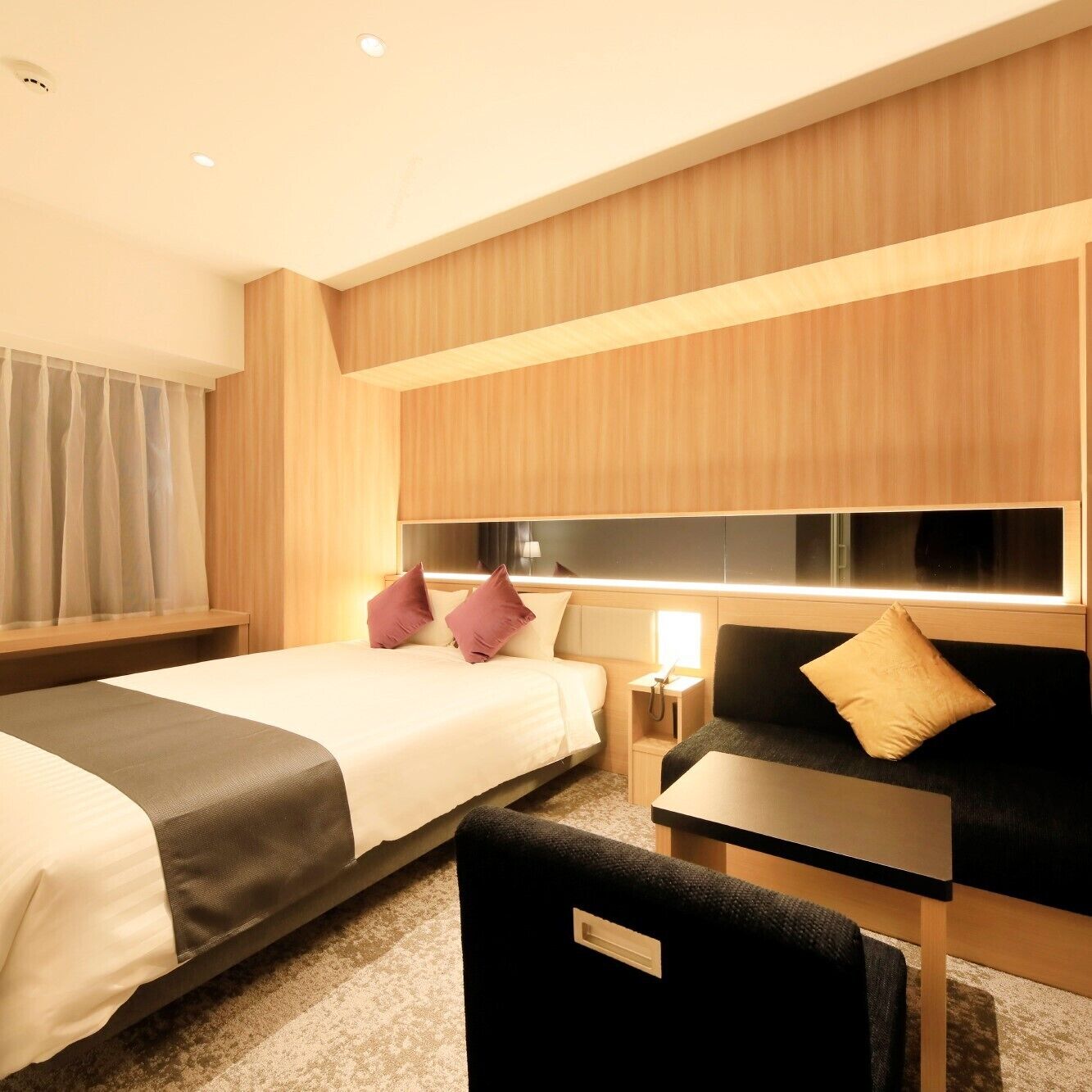 Une chambre d’hôtel avec un lit, un canapé, une petite table et une table de chevet.