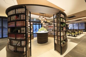 A modern library with bookshelves, a central reading area, and seating. - Quintessa Hotel Fukuoka Tenjin Comic & Books (Fukuoka)