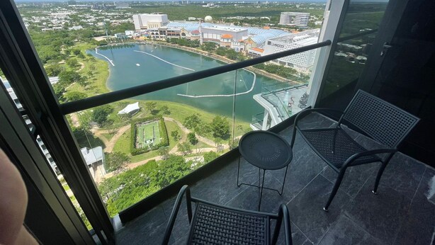 Un balcon offrant une vue sur un paysage urbain, avec notamment un vaste plan d’eau et des bâtiments.
