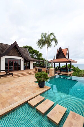A resort with a swimming pool, a covered seating area, and a view of the ocean. - Villa Baan Hen 5 Bedroom Kata Beach (Karon)
