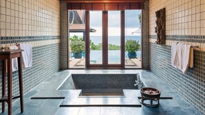 A bathroom with a large bathtub, a shower, and a view of the sea through a glass door. - Villa Baan Hen 5 Bedroom Kata Beach (Karon)