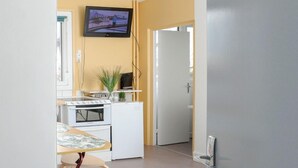 A modern kitchen with a TV, a dining table, and a chair. - Studio Cosy et Fonctionnel, Proche de Paris (Villeneuve-la-Garenne)