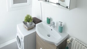 A modern bathroom with a washing machine, a sink, a mirror, and a radiator. - Studio Cosy et Fonctionnel, Proche de Paris (Villeneuve-la-Garenne)