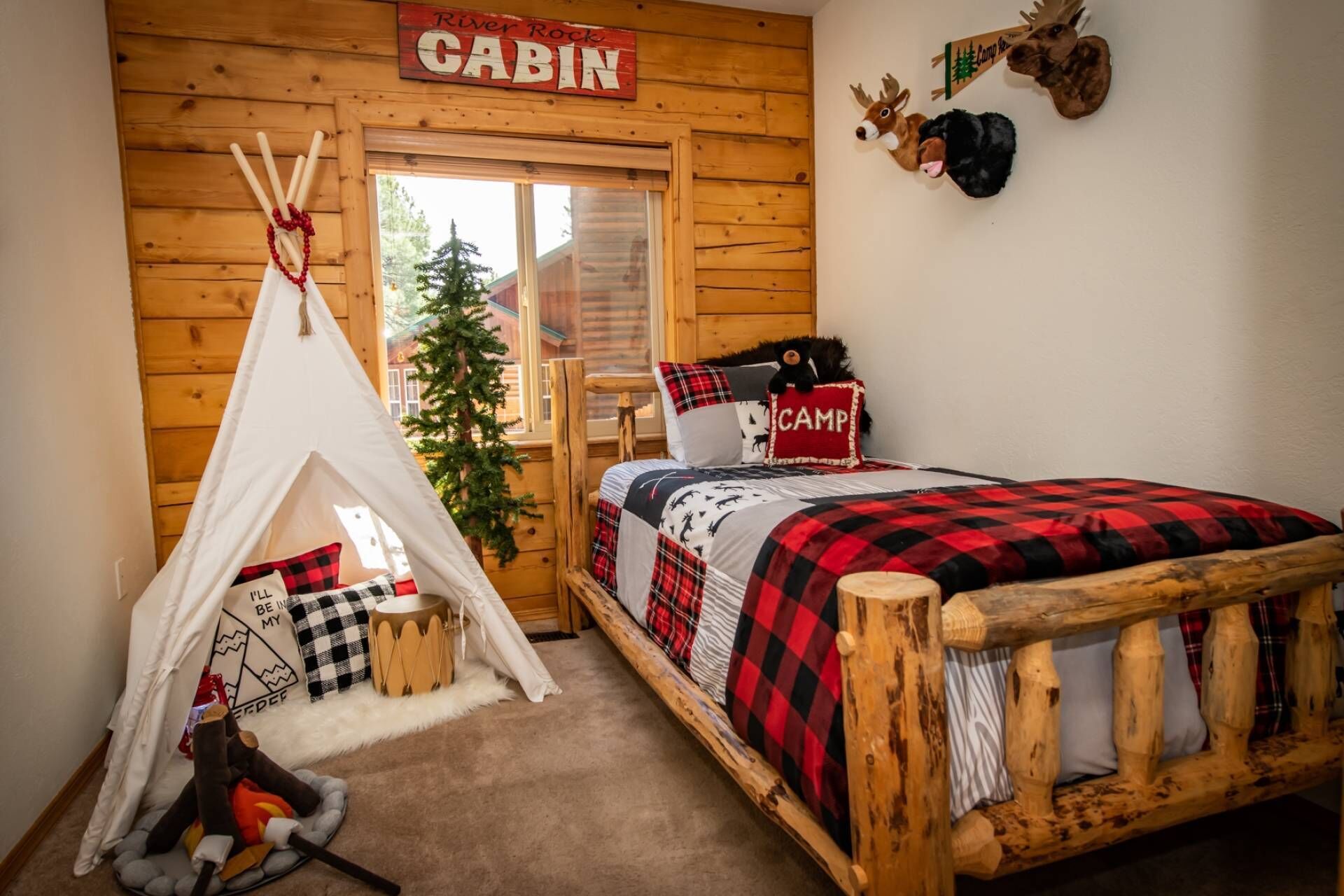 A cabin-themed bedroom with a bed, a teepee, and a Christmas tree.