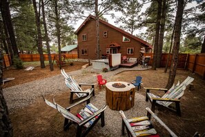 A log cabin with a deck, outdoor seating, and a fire pit.