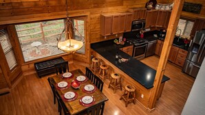 A wooden cabin interior with a dining area, kitchen, and bar. - Hot Tub, Arcade Room, Fire Pit, 3 Min to Uptown Pagosa, Private Colorado Setting (Pagosa Springs)