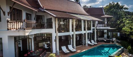 A large house with a swimming pool, multiple balconies, and outdoor seating areas.