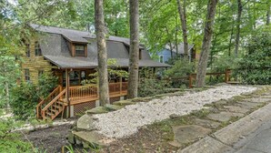 A log cabin with a wooden deck and a stone pathway leading to the entrance. - Charming Cabin with Fire Pit (Arden)