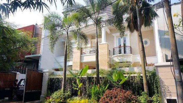 A multi-story residential building with balconies, surrounded by lush greenery and palm trees. - KoolKost Syariah near Pondok Indah Mall (Jakarta)
