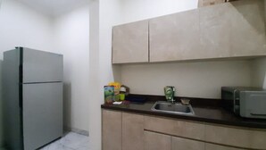 A compact kitchen with a refrigerator, a sink, and cabinets. - KoolKost Syariah near Pondok Indah Mall (Jakarta)