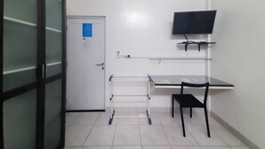 Habitació amb escriptori, cadira i televisió penjada a la paret.