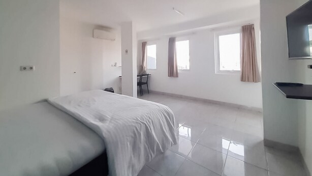 Una habitació d'hotel àmplia amb un llit gran, un escriptori i una televisió.