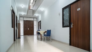 A hallway with a wooden door marked 103, a tiled floor, and a table with chairs.