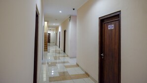 Un passadís amb sòl de rajola, portes de fusta i un senyal amb un número en una porta.