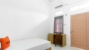 Ein Schlafzimmer mit Bett, Schreibtisch, Stuhl, Kleiderschrank und Klimaanlage.