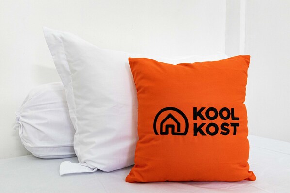 Dos almohadas, una blanca y otra naranja con un logotipo y texto.