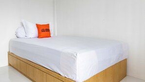 Ein Einzelbett mit weißer Matratze und Holzrahmen.