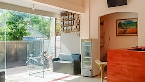 A spacious room with a large window, a sofa, a refrigerator, and a television mounted on the wall. - Waringin Residence (Medan)