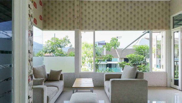 Una sala moderna con un sofá, sillones y una mesa de centro. Amplias ventanas ofrecen vistas al exterior.
