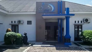 Um edifício com design moderno, destacando uma entrada imponente com um pilar azul e um logotipo acima da porta.