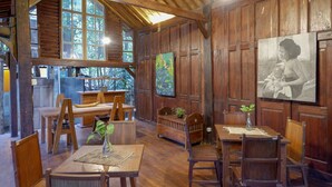 A rustic wooden interior with a dining area, wooden benches, and a painting on the wall. - Upala Java Huise (Bangunjiwo)